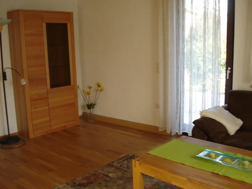 Wohnzimmer mit Sofa, Vitrine und Terrassenzugang